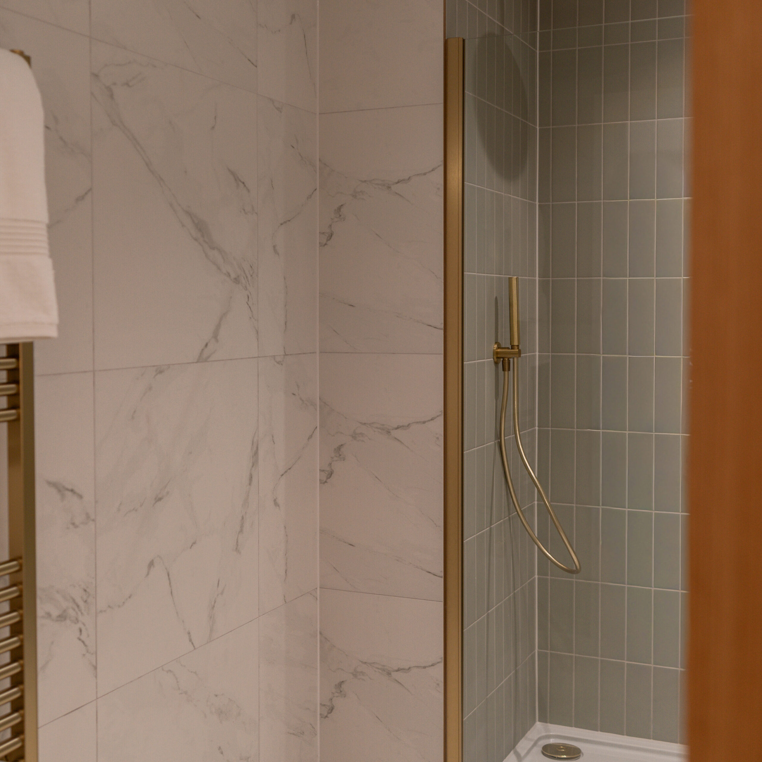 Shot of the ensuite on the main bedroom, marble tiling with gold feature finishes and sage green tiling within the shower